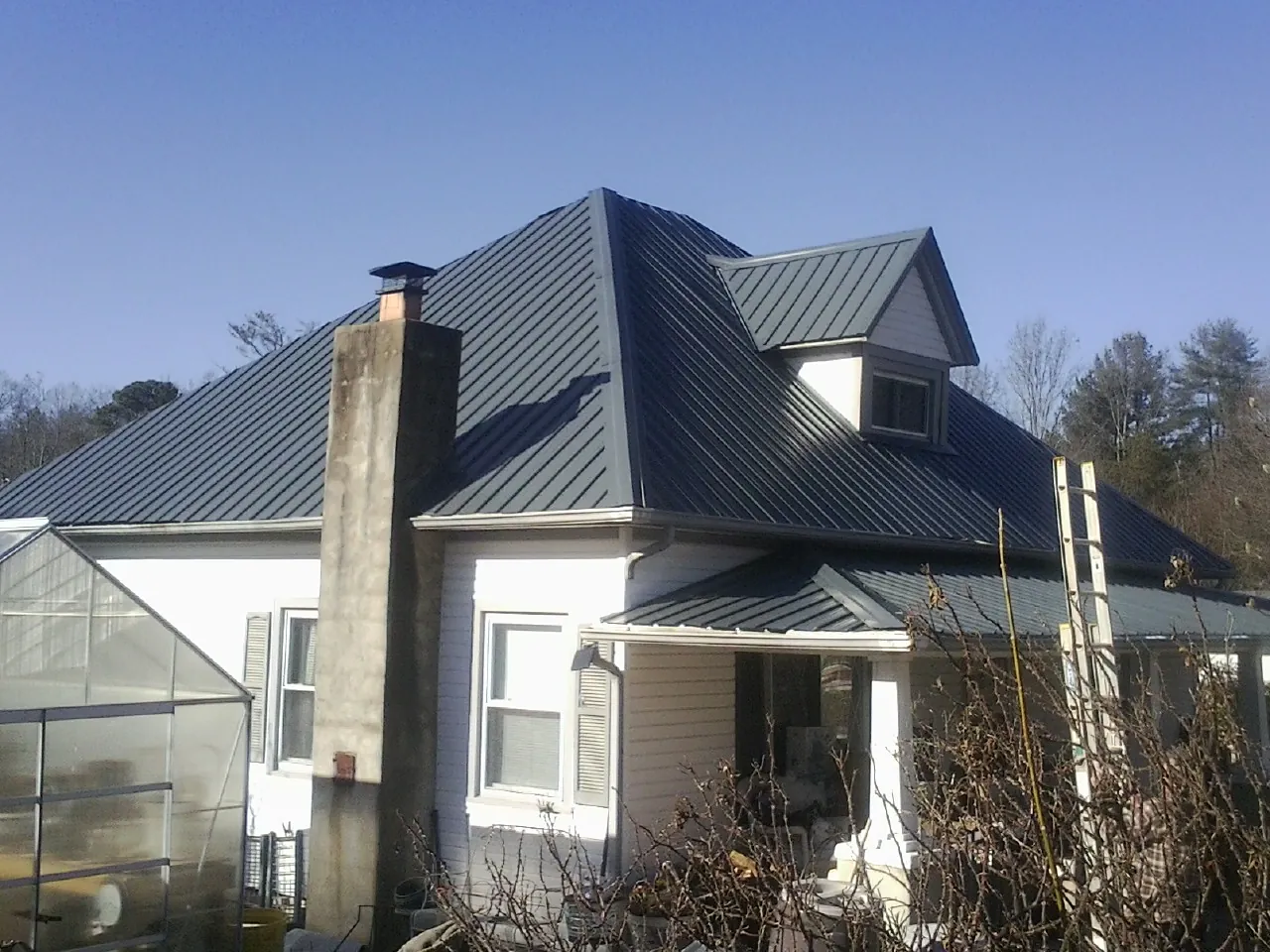 Dark blue standing seam metal roof on a white farmhouse with dormer — Slate & Tile Roof Repair by Roofing Brothers in Struthers