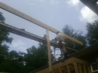 Carpenter setting a ridge beam over a new addition frame — Ice Dam Removal by Roofing Brothers in Struthers