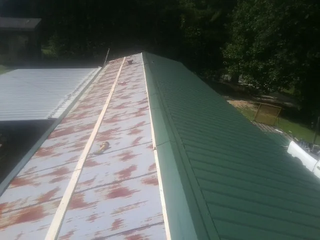 Old rusted panels beside newly installed green metal roofing — Wind Damage Roof Repair by Roofing Brothers in Struthers