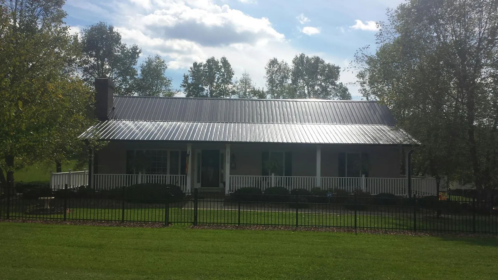 Gray metal roof on a brick ranch with a full width front porch — Gutter Guard Installation work by our crew in Struthers
