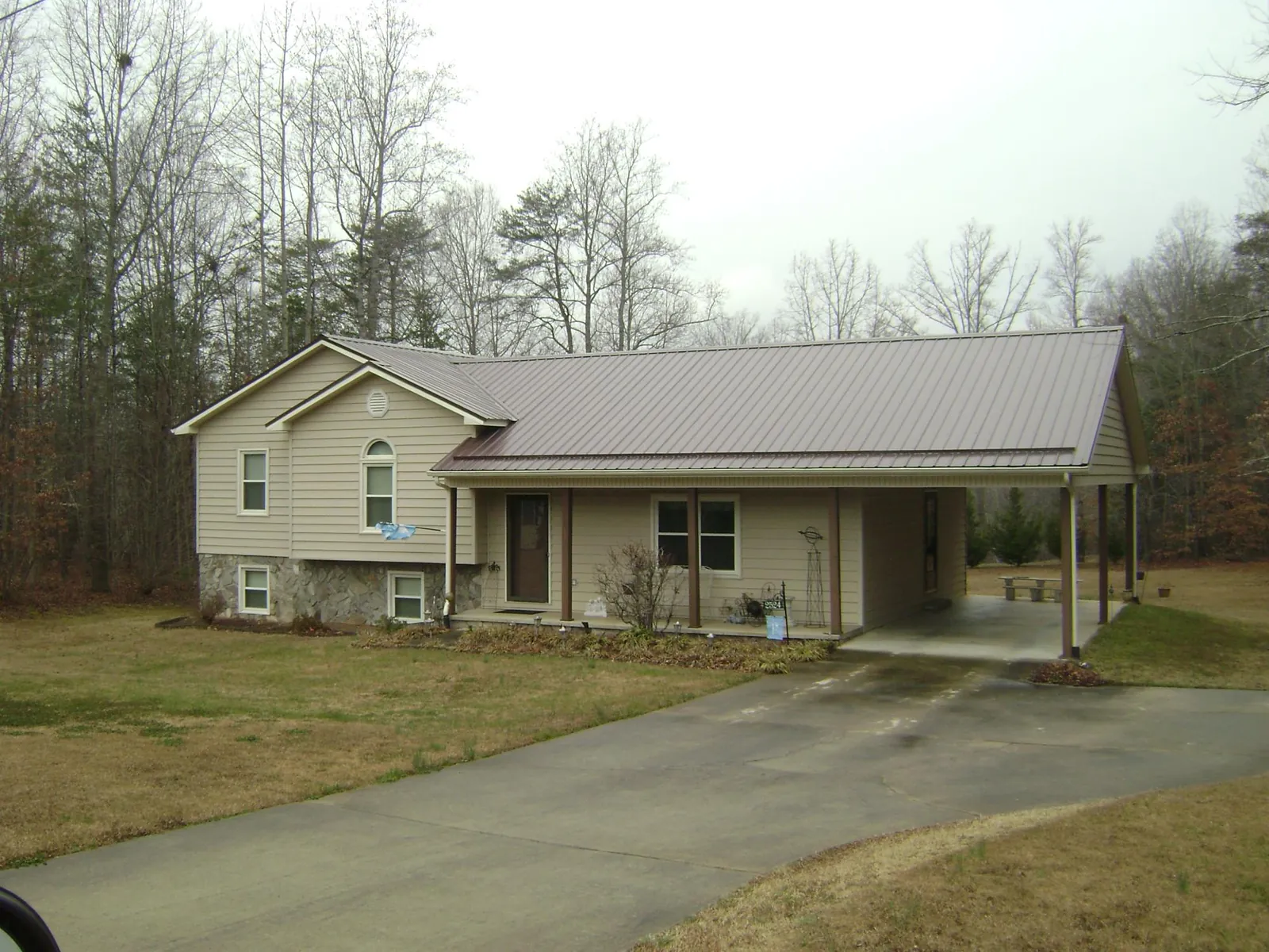 Brown metal roof on a tan split level home with an attached carport in Struthers