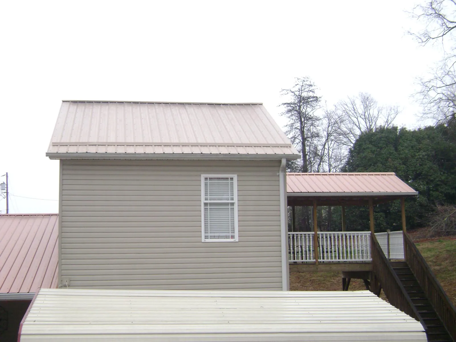 Tan metal roofs on a two story addition and attached porch, from a Roof Replacement job in Struthers