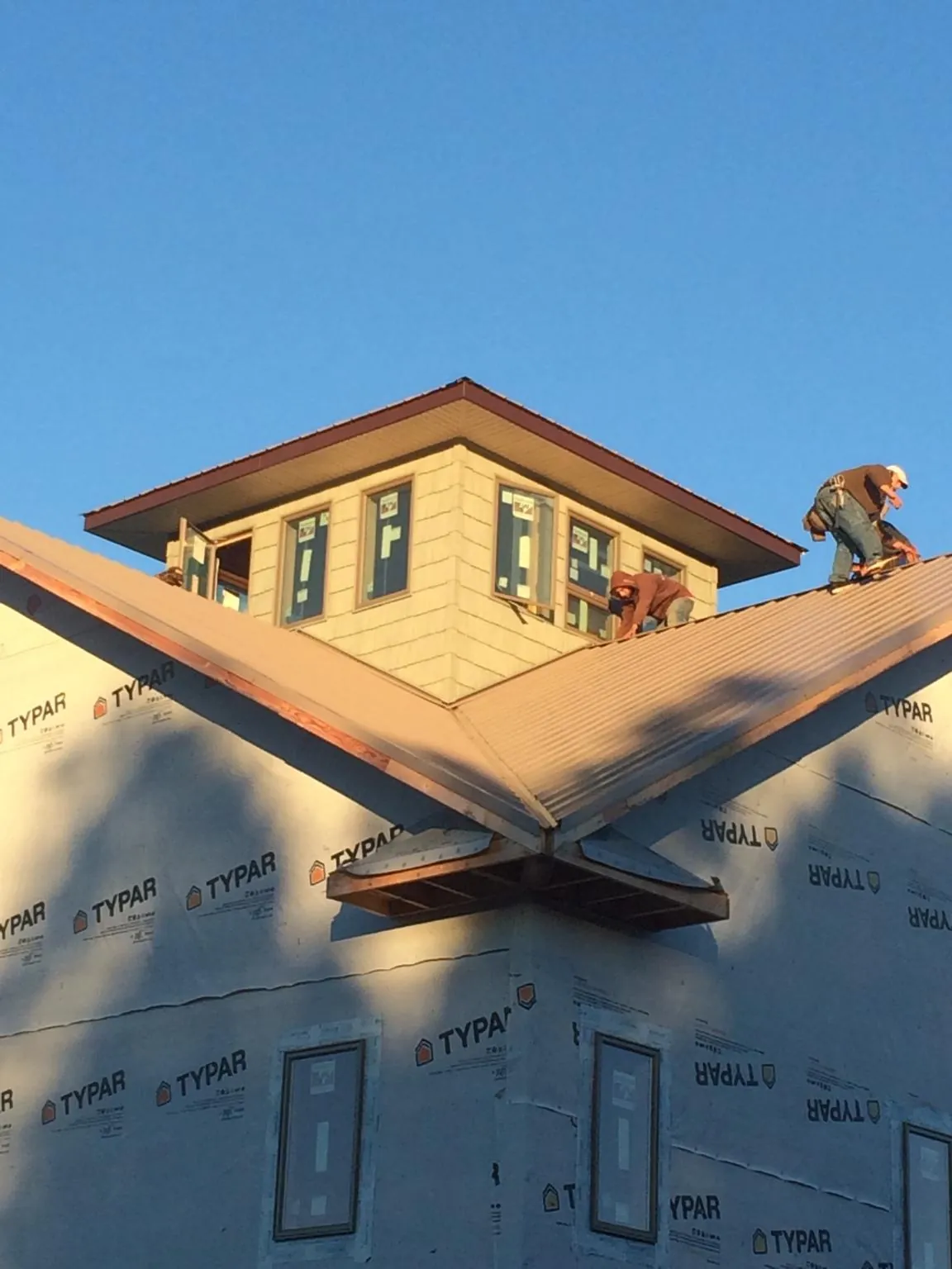 Roofers working around a rooftop cupola on a new metal roof at sunset — Roof Waterproofing in Struthers by Roofing Brothers
